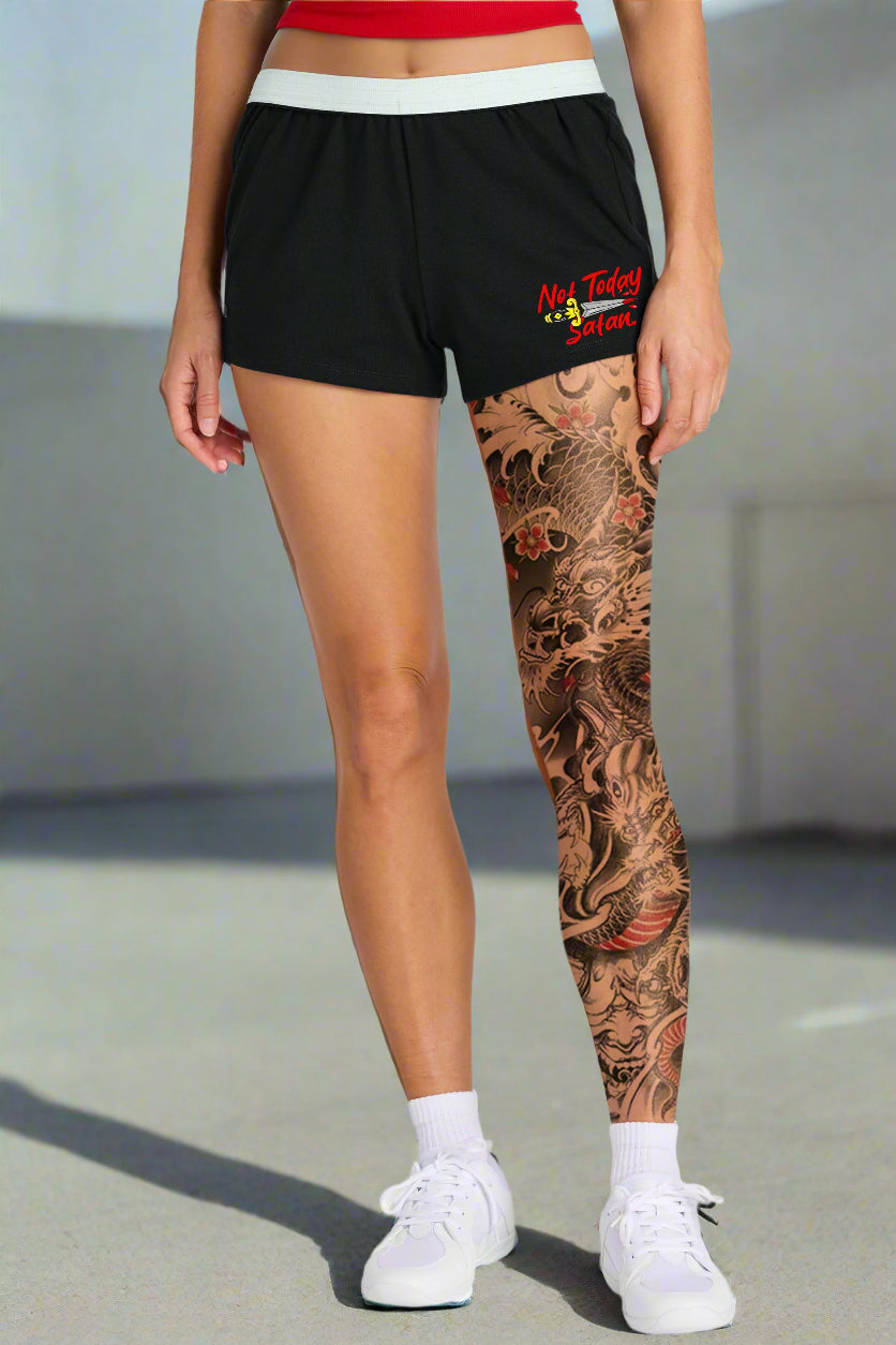 Person wearing black shorts with a brand logo and patterned leggings on a white background